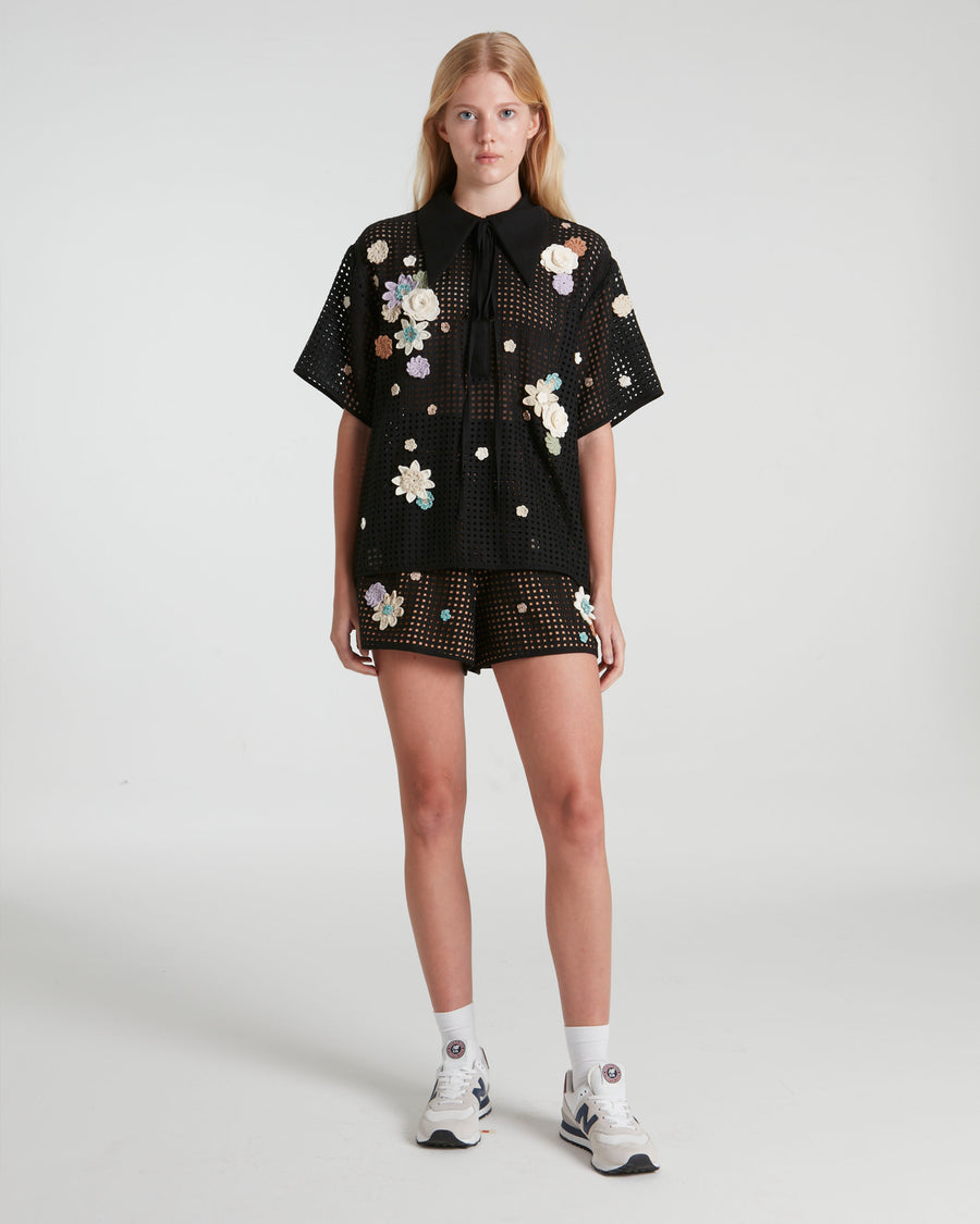 Black stenciled shorts decorated with knitted flowers